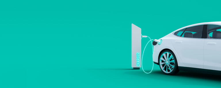 White,Electric,Car,Connected,To,Power,Station,Charger,On,Green